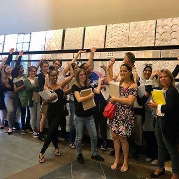 Happy ITMD students standing in front of a sample wall, waving their hands