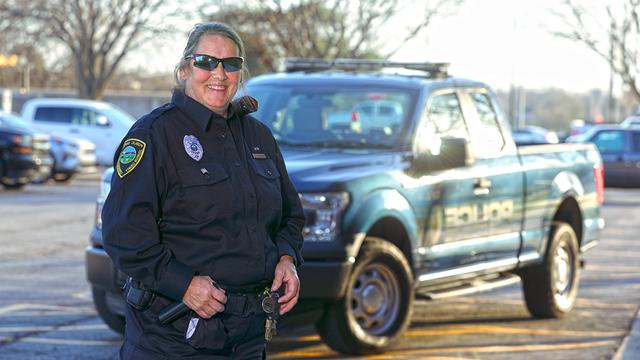 Officer Kathy Rhoades wearing her police uniform and standing in front of a police pickup truck